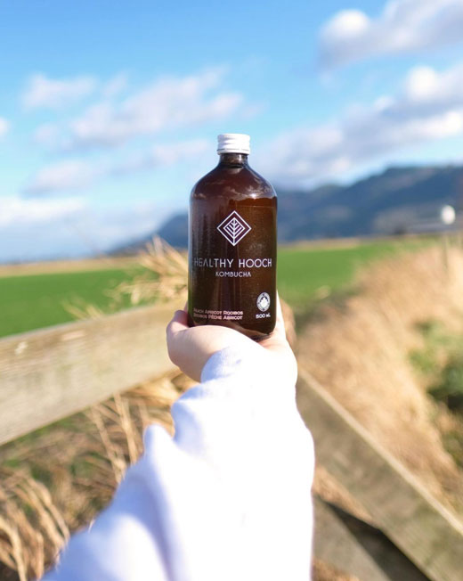 bottle of certified organic healthy hooch with the farm in the background