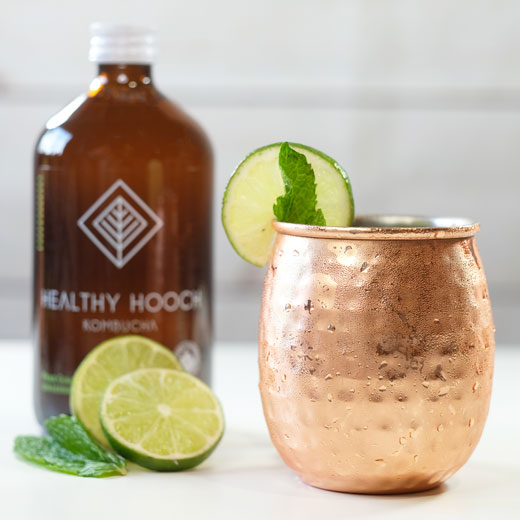 moscow mule next to a bottle of healthy hooch with some limes