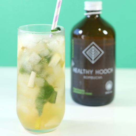 pear ginger mojito mocktail next to a bottle of healthy hooch kombucha