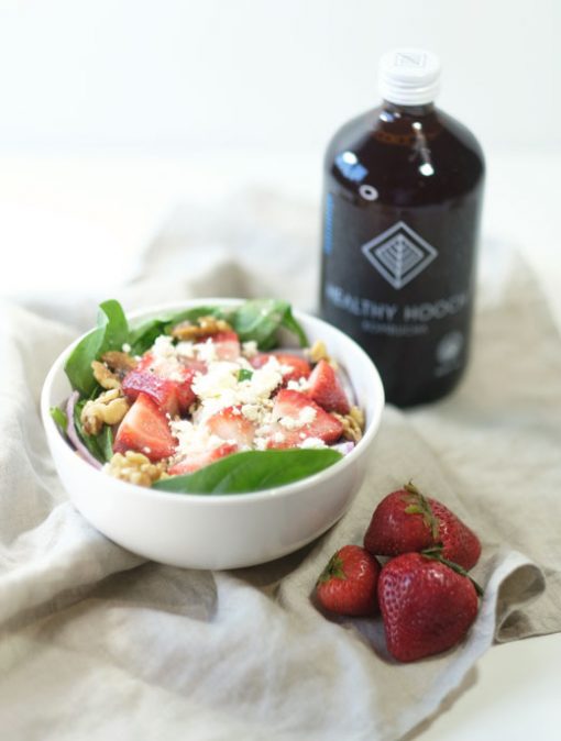 summer salad next to some strawberries and a bottle of healthy hooch kombucha