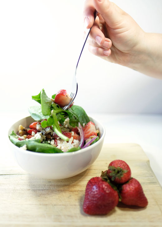 persons hand grabbing a fork full of summer salad